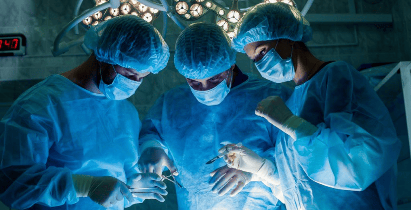 Surgical team in protective gear performing a procedure in a sterile environment.